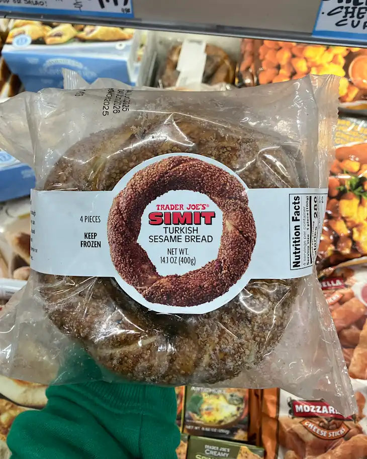 Frozen package of Trader Joe's Simit, Turkish sesame bread, with four pieces visible and a green sweater in the foreground.