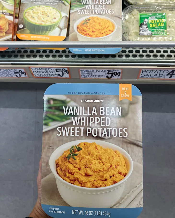 Container of Trader Joe's Vanilla Bean Whipped Sweet Potatoes with a serving suggestion in a white bowl, displayed in a grocery aisle.
